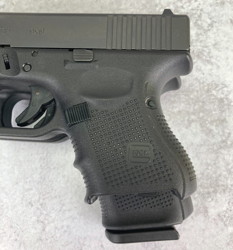 Glock 26 with magazine removed, laid overtop of Glock 19. Glock 26 has a shorter slide and frame, but a reduced capacity.