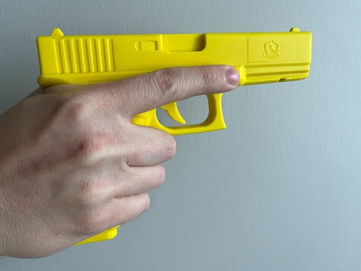 hand holding a yellow plastic gun demonstrating trigger control